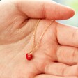 Model Holding Tiny Red Enamel Heart Necklace