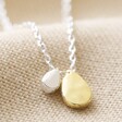 Close Up of Organic Hammered Droplet Charm Necklace in Silver on Beige Fabric