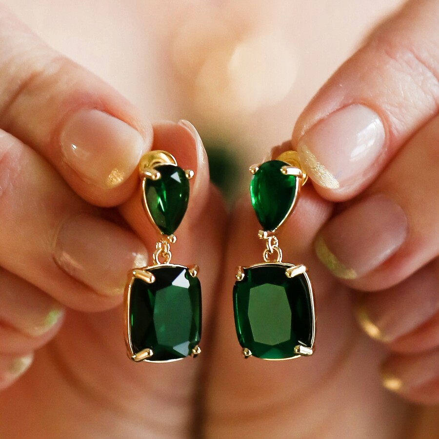 Model holding Big Metal London Gemstone Drop Earrings in Emerald Green