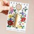 model holding Beevive Bamboo Bee Revival Kit Keyring in Gold in packaging