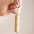 model holding Beevive Bamboo Bee Revival Kit Keyring in Gold in finger by keyring