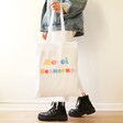 model holding Merci Beaucoup Cotton Tote Bag in White by the straps