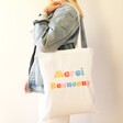 Model Carrying Merci Beaucoup Cotton Tote Bag in White on their shoulder
