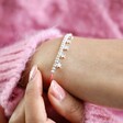 Close up of model wearing Estella Bartlett Pastel Rainbow Cord and Stars Bracelet 