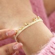 Close up of model wearing Estella Bartlett Woven Star Charm Bracelet in Gold