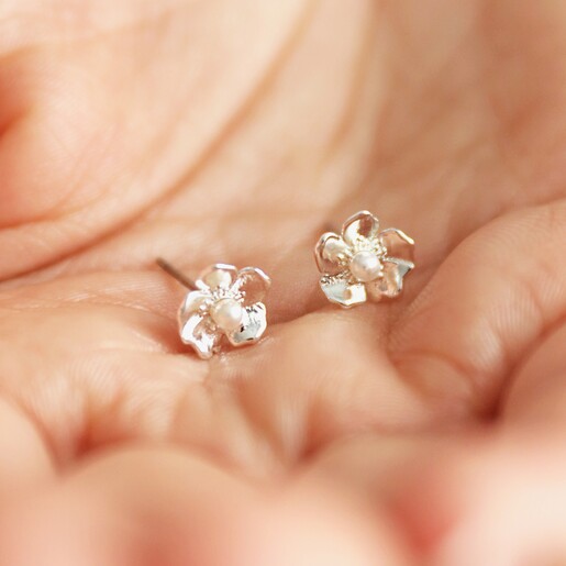 Model holding Estella Bartlett Silver Pearl Buttercup Stud Earrings