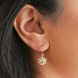 Close Up of Estella Bartlett Sun Charm Drop Earrings in Gold on Model
