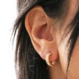 close up of model wearing Estella Bartlett Woven Hoop Earrings in Gold
