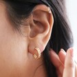 close up of model tucking hair behind ear and wearing Estella Bartlett Woven Hoop Earrings in Gold