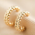 Estella Bartlett Woven Hoop Earrings in Gold on fabric background