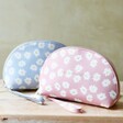 Estella Bartlett Daisy Half Moon Make Up Pouch in Blue or Pink sat on wooden table against green background