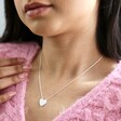 Model wearing Estella Bartlett Love Engraved Heart Pendant Necklace with pink jumper