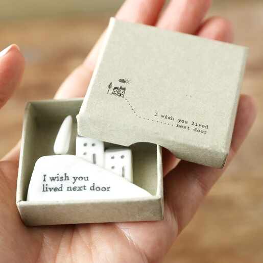 model holding East of India Wish You Lived Next Door House Ornament box open with ornament inside