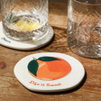 Personalised Orange Fruit Organic Shape Coaster on Wooden Table with Glasses in Background