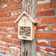 Wooden Bee House Hanging on Wooden Plank on Side of Red Brick House