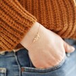 Model wearing Rose Gold Feather Bracelet with hand in jean pocket