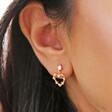 close up of model wearing drop earring from Mismatched Crystal Heart Earrings in Gold