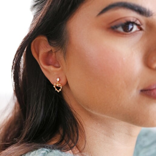 Model looking off to the side wearing drop earring from Mismatched Crystal Heart Earrings in Gold