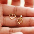 model holding Mismatched Crystal Heart Earrings in Gold in between fingers