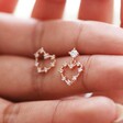 model holding Mismatched Crystal Heart Earrings in Rose Gold in between fingers