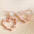 Mismatched Crystal Heart Earrings in Rose Gold on fabric background
