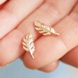 Model holding Rose Gold Feather Stud Earrings