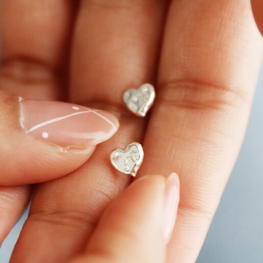 Model holding Small Hammered Heart Stud Earrings in Silver in palm of her hand