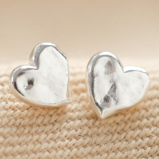 Small Hammered Heart Stud Earrings in Silver on fabric background