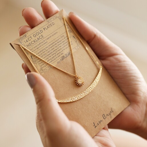 Model Holding Sun and Horn Layered Necklace in Gold in Packaging