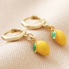 Enamel Lemon Huggie Hoop Earrings in Gold on Beige Fabric