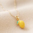 Close Up of Lemon on Enamel Lemon Pendant Necklace on Beige Fabric