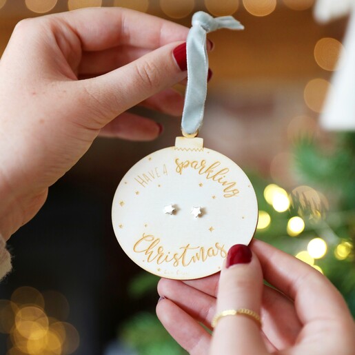 Model Holding Lisa Angel Sterling Silver Star Stud Earrings on Wooden Bauble
