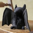 Jellycat Bewitching Bat Soft Toy sat on wooden chair