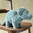 side view of Jellycat Fossilly Triceratops Soft Toy sat on wooden table