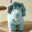 Jellycat Fossilly Triceratops Soft Toy sat on wooden table facing camera