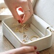 model lifting out earring from bottom layer of personalised mother's day natural linen jewellery case