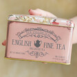 Model Holding English Breakfast Tea Bags in Floral Tea Tin