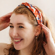 model wearing Twist Fabric Headband in Orange and White