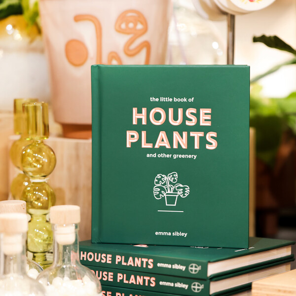 The Little Book of House Plants and Other Greenery book stacked on top of more copied with candle holder and planter