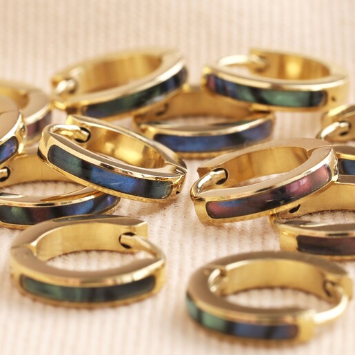 Shell Black Resin Infill Huggie Hoop Earrings in Gold on Beige Fabric