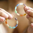 Model Holding Colourful Glass Beaded Hoop Earrings in Gold