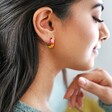 side profile of model wearing Rainbow Geometric Enamel Hoop Earrings in Gold