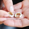 Model Holding White Geometric Enamel Hoop Earrings in Gold
