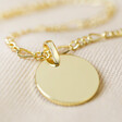 close up of disc from Disc and Figaro Chain Necklace in Gold on fabric background