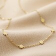 Long Starry Necklace in Gold on Beige Fabric