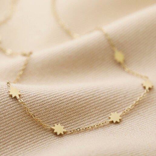 Long Starry Necklace in Gold on Beige Fabric
