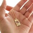 Model Holding Enamel Love Tarot Card Style Necklace in Gold