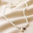 White Beaded Shell Charm Necklace on Beige Fabric
