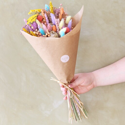 model holding Pastel Easter Dried Flower Bouquet  in front of green background