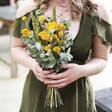 Model Holding Eucalyptus and Yellow Dried Flower Wedding Posy